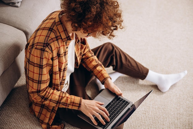 Zdjęcie młody mężczyzna pracujący na laptopie w domu siedzący na kanapie