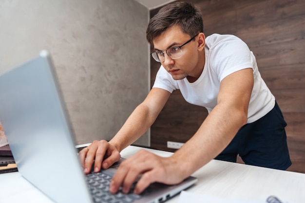 Młody mężczyzna pracujący w domu przy użyciu laptopa
