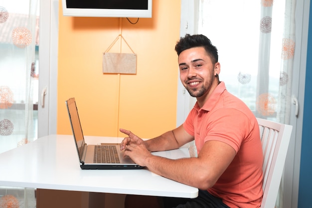 Młody mężczyzna pracujący w domu z laptopem