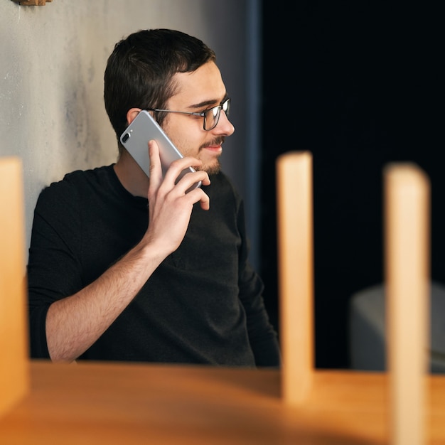 Młody mężczyzna pracujący z telefonem i komputerem, odbierający telefon, rozmawiający z partnerami