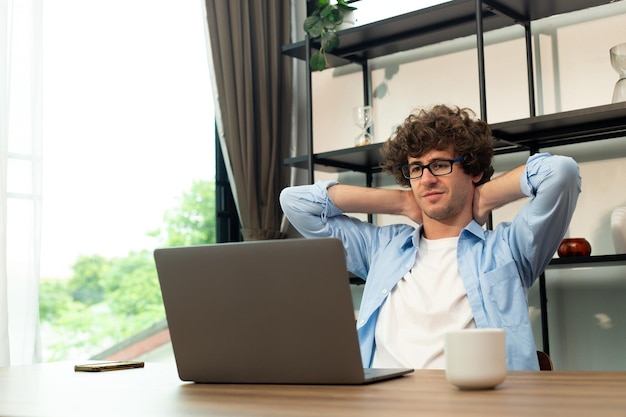 Młody mężczyzna rasy kaukaskiej pracuje z domu na laptopie i łączy się online z biurem w pomieszczeniu w celu zdalnego dostępu do Internetu Młody dorosły mężczyzna jest niezależny, pracuje mądrze na notebooku, siedzi w pokoju roboczym