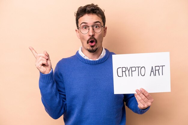 Młody mężczyzna rasy kaukaskiej trzymający afisz sztuki kryptograficznej na białym tle na beżowym tle, skierowany w bok