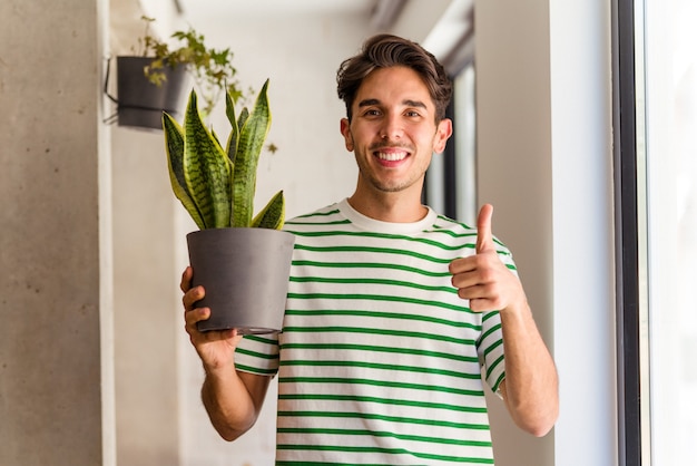 Młody mężczyzna rasy mieszanej z rośliną w swoim domu