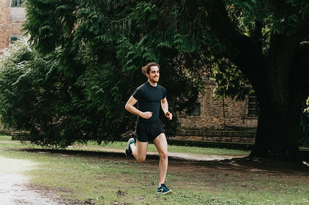 Młody mężczyzna robi sprint w parku podczas treningu fitness