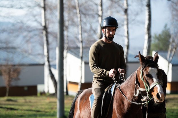 Młody mężczyzna siedzący na koniu na zewnątrz