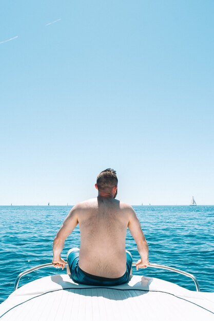Młody mężczyzna siedzący na pokładzie łodzi nad Morzem Śródziemnym