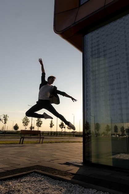 Młody mężczyzna skacze przed szklaną ścianą z napisem „taniec”.