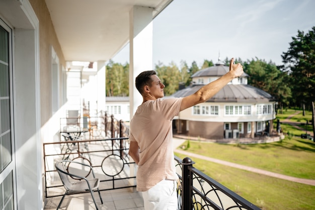 Młody Mężczyzna Stoi Na Hotelowym Balkonie I Robi Sobie Selfie Telefonem Komórkowym