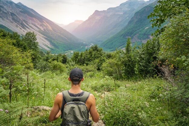 Młody mężczyzna trekking na szczycie zielonej góry między paprociami