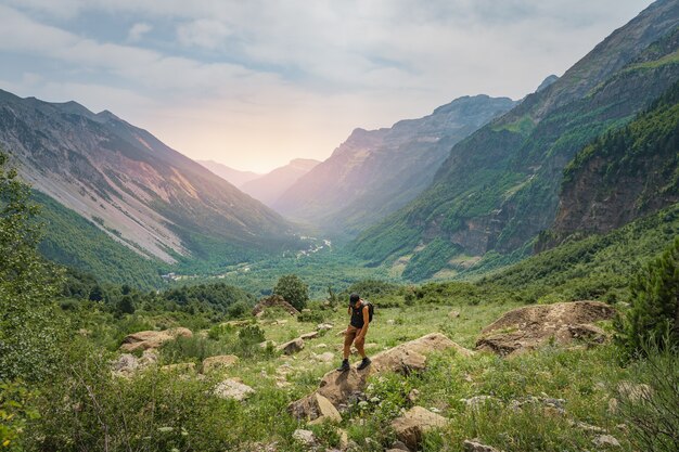 Młody mężczyzna trekking na szczycie zielonej góry podczas zachodu słońca