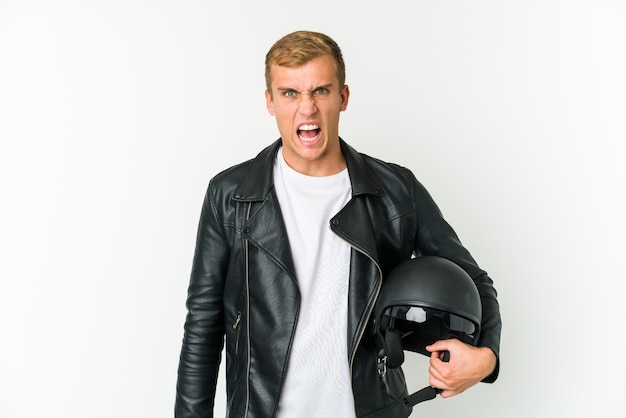 Młody mężczyzna trzyma kask motocyklowy krzyczy bardzo zły i agresywny