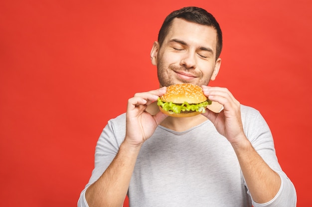 Młody mężczyzna trzyma kawałek hamburgera