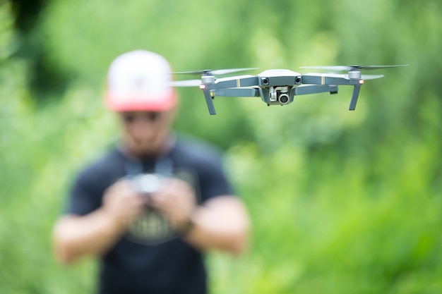 Młody Mężczyzna Trzyma Pilota I Latanie Z Dronem W Parku.