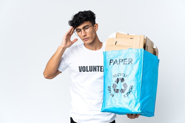 Młody mężczyzna trzyma torbę recyklingu pełnego papieru z bólem głowy