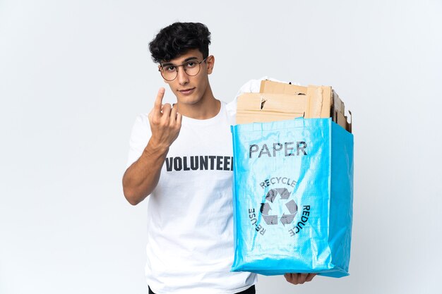 Młody mężczyzna trzyma worek recyklingu pełnego papieru robi nadchodzący gest