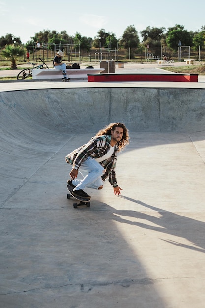 Młody mężczyzna uprawiający surfskate w skateparku podczas zachodu słońca