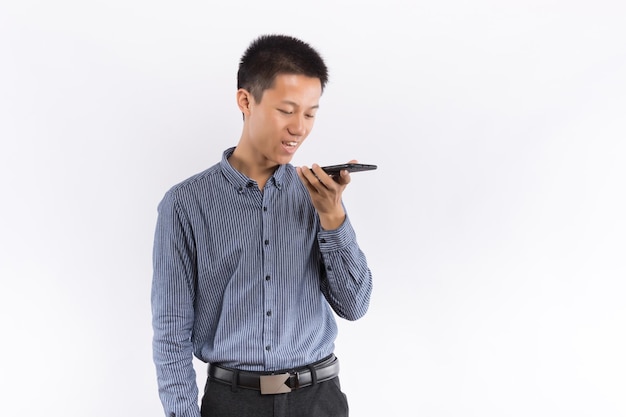 Młody mężczyzna używa telefonu komórkowego przed białym tłem
