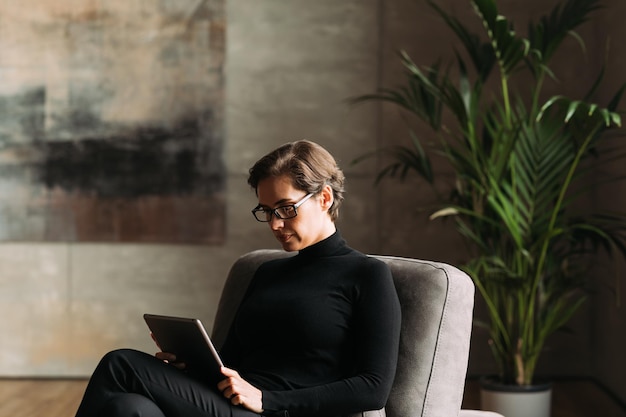 Młody mężczyzna używający laptopa siedząc przy ścianie
