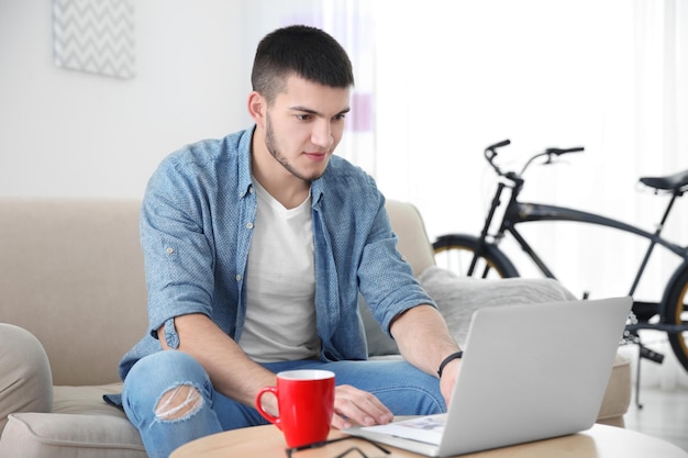 Młody mężczyzna używający laptopa w domu