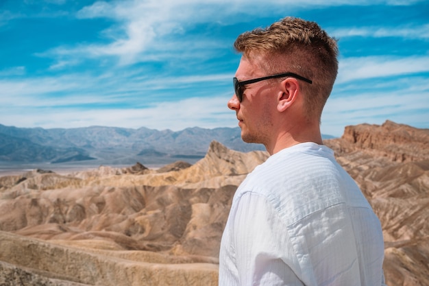 Młody mężczyzna w białej koszuli przemierza malowniczą pustynię w Dolinie Śmierci