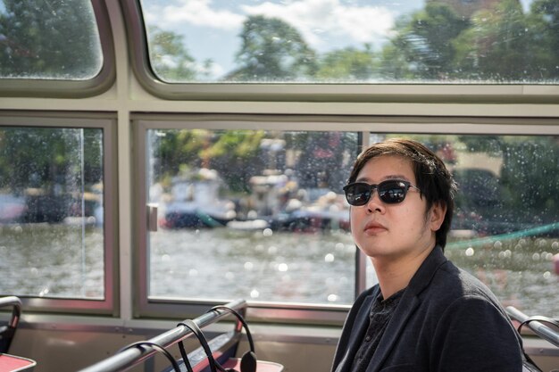 Zdjęcie młody mężczyzna w okularach przeciwsłonecznych siedzący przy oknie w autobusie