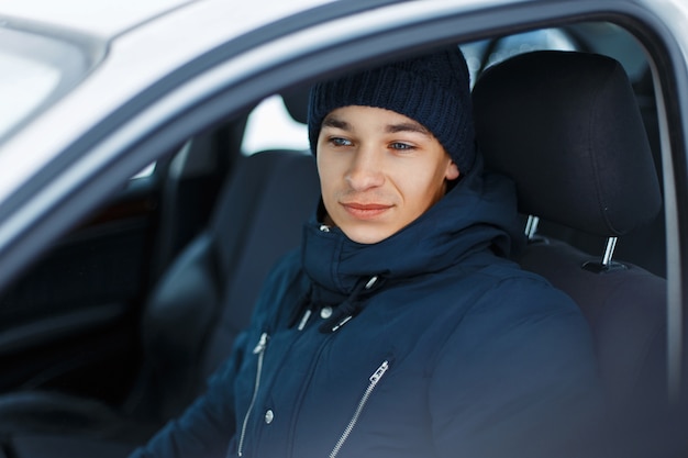 Młody mężczyzna w zimowej odzieży siedzi w samochodzie