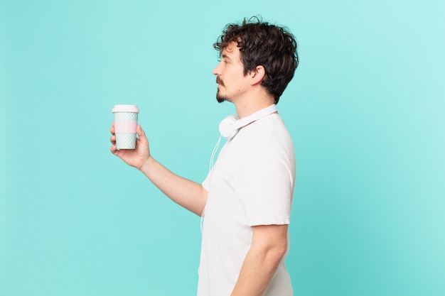 Młody mężczyzna z kawą na widoku profilu myślący, wyobrażający sobie lub marzący
