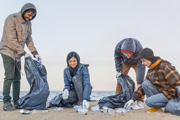 Młody mężczyzna zbiera śmieci i plastik z grupą wolontariuszy na plaży