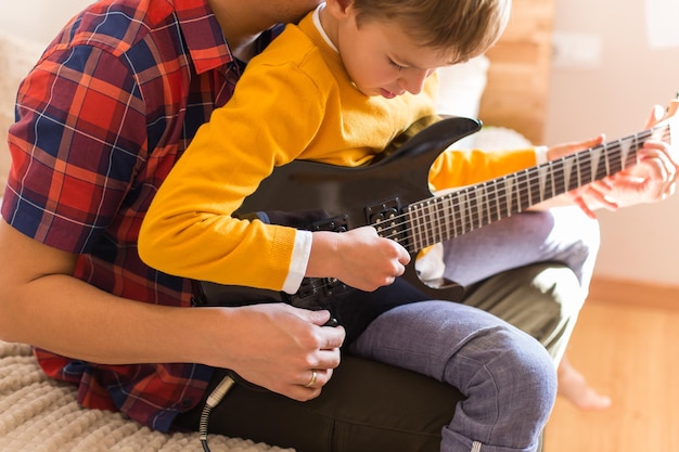 Młody millenialsi ojciec i słodki syn grają na gitarze elektrycznej Pozostań w domu, aktywność w domu, nauka, zajęcia, rodzina, wspólna zabawa