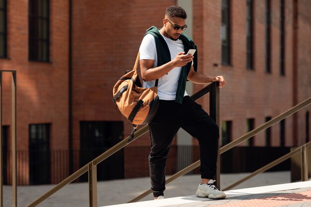 Młody Murzyn używający telefonu spacerujący po mieście