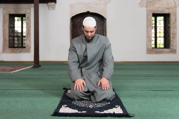 Młody muzułmanin odmawiający tradycyjną modlitwę do Boga, nosząc tradycyjną czapkę Dishdasha
