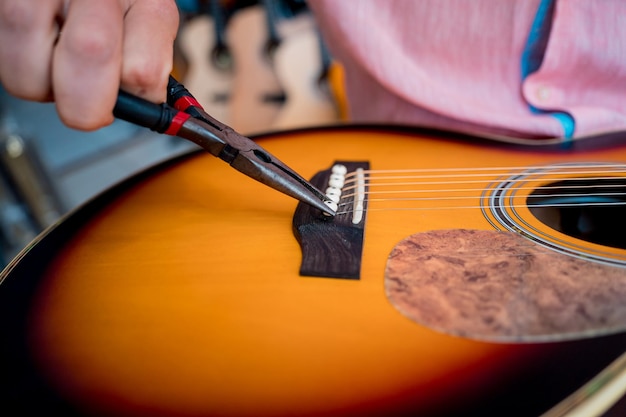 Młody muzyk zmienia struny na gitarze klasycznej w sklepie z gitarami
