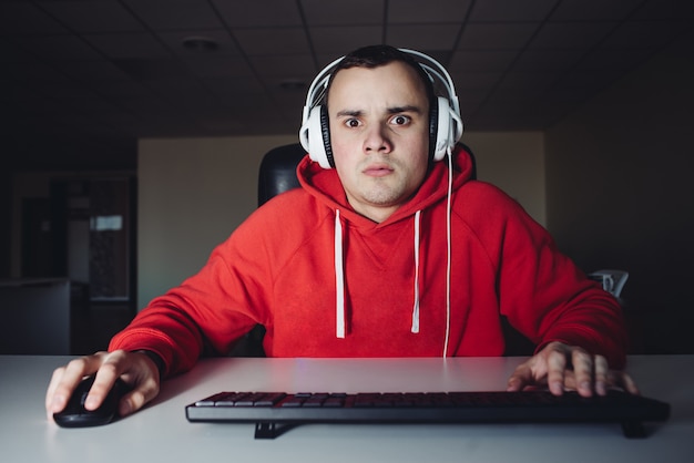 Zdjęcie młody nastolatek gracz gra w domu na swoim komputerze. młody człowiek ze strachem przed spojrzeniem na monitor komputera