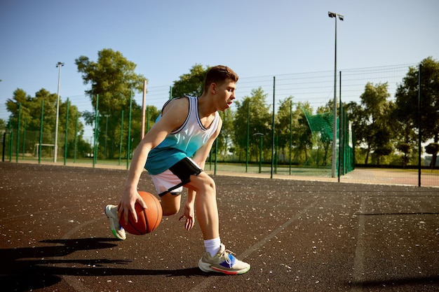 Młody nastolatek trenujący na boisku ulicznym grający w koszykówkę Aktywny czas na sport i zdrowy styl życia