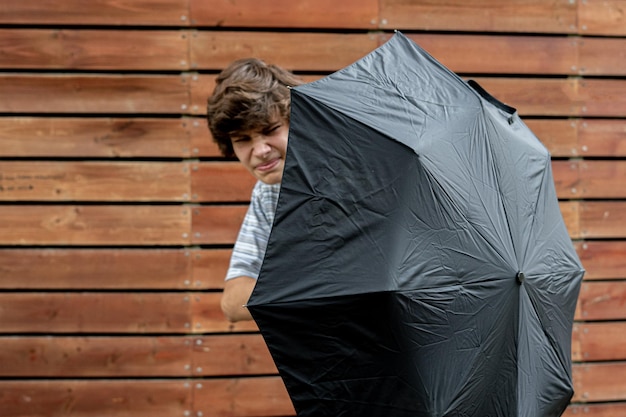 Młody nastolatek trzymający parasol chroniący się przed problemem
