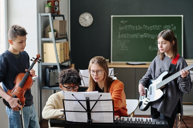 Zdjęcie młody nauczyciel muzyki pracujący z szkolnym zespołem