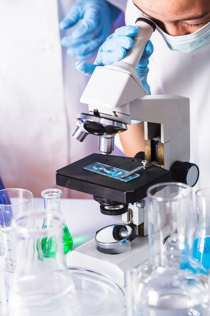 Młody naukowiec spogląda w okular mikroskopu w laboratorium chemicznym