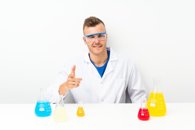 Młody naukowiec z dużą ilością kolb laboratoryjnych wskazuje na ciebie palcem