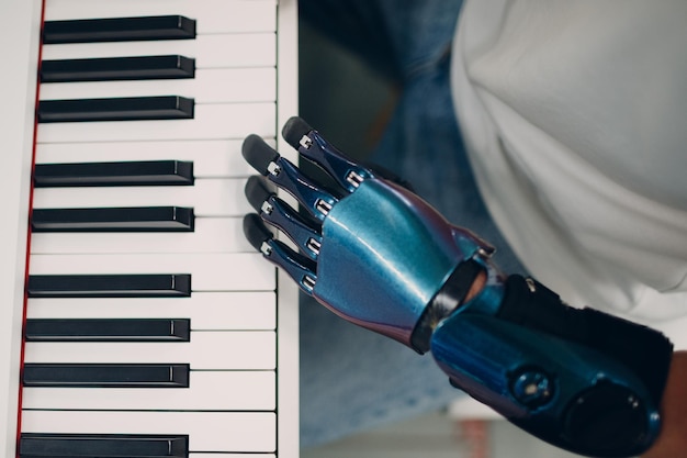 Młody niepełnosprawny mężczyzna gra na fortepianowym syntezatorze elektronicznym ze sztuczną protezą ręki w sklepie muzycznym