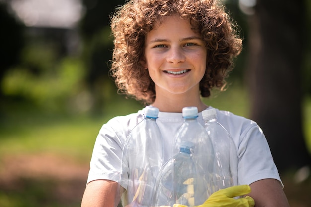 Młody ochotnik z kręconymi włosami zbiera plastikowe butelki