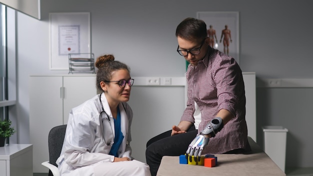 Młody pacjent z bioniczną ręką buduje wieżę z drewnianych klocków w centrum rehabilitacji