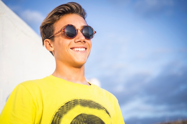 młody piękny męski uśmiech nastolatka odkryty z błękitnego nieba. obraz koncepcji w stylu letnim