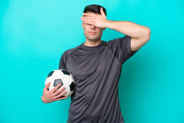 Młody piłkarz kaukaski mężczyzna na białym tle na niebieskim tle zakrywający oczy rękami Nie chcę czegoś widzieć