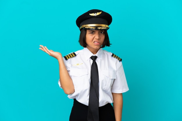 Młody pilot samolotu na odosobnionym niebieskim tle ma wątpliwości