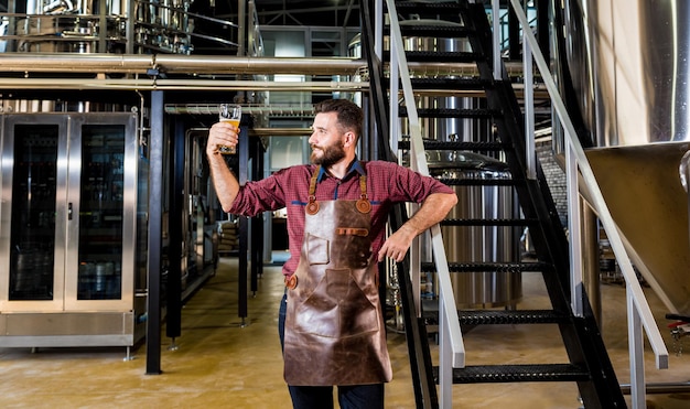 Zdjęcie młody piwowar mężczyzna w skórzanym fartuchu w nowoczesnej fabryce browaru