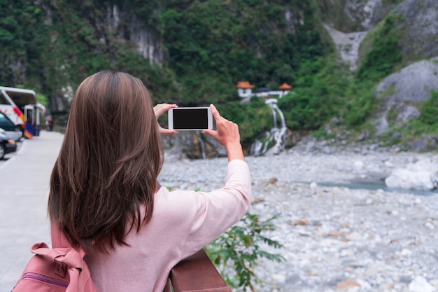 Młody podróżnik dziewczyny mienia telefon komórkowy podczas gdy brać fotografię Changchun świątynia, Taroko, Taiwan