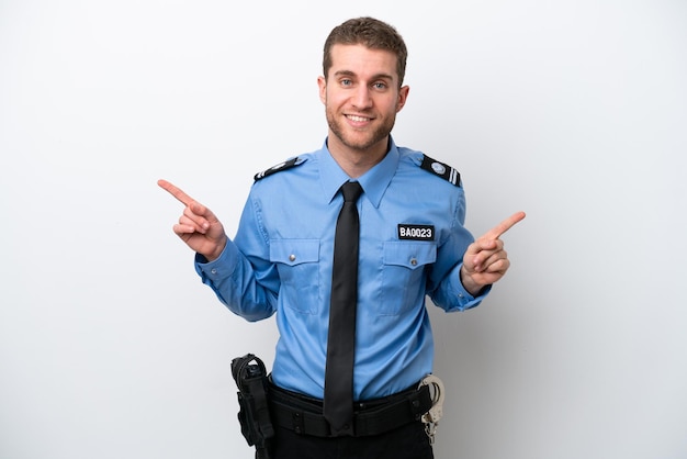 Młody policjant kaukaski mężczyzna na białym tle wskazujący palec na boki i szczęśliwy