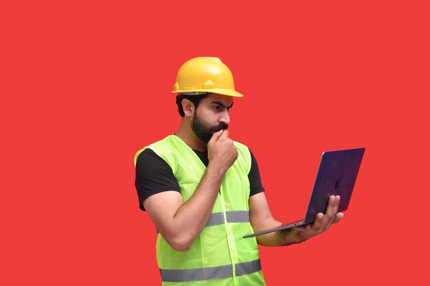 młody pracownik budowlany przekazuje usta i trzyma laptopa indyjski model pakistański