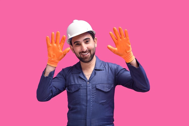 młody pracownik budowlany uśmiechający się i pokazujący rękawice ochronne indyjski model pakistański