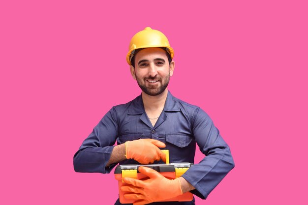 młody pracownik budowlany uśmiechający się i trzymający skrzynkę narzędziową indyjski model pakistański